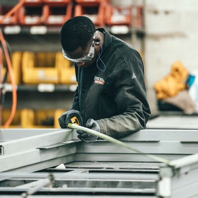 man wearing goggles works on machinery in a factory